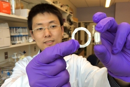 Shiyi Zhang, a postdoc at the Koch Institute and the paper’s lead author, holds a ring-shaped device prototype (left), which can be folded into a swallowable capsule (right) for easy and safe oral delivery.