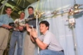 MIT researchers in the Department of Aeronautics and Astronautics stand with the instrumented truss that is key to the first hands-on experiment aboard the International Space Station. Left to right are Sophomore Cemocan Yesil, Associate Professor David Miller, Postdoctoral Fellow Gregory Mallory, and Graduate Student Jeremy Yung.