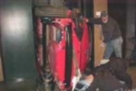 Workers load the car into an elevator shaft.
