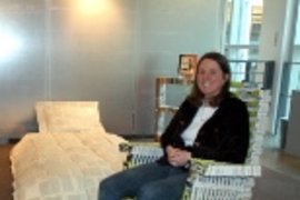 Stephanie Hartman relaxes in a rocking chair she made out of campus phone directories, part of a book-based bedroom suite on view in Rotch Library.