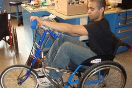 James Levi Schmidt, a member of an MIT class on wheelchair design for the developing world, tests a prototype of a wheelchair that was converted into a tricycle powered by hand-operated pedals.