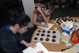 Senior Angie Chiang, foreground, and junior Taylor Williamson write notes on the chemistry they have learned by making "Death by Chocolate" cookies in Patti Christie's Kitchen Chemistry course, offered in the ESG kitchen.