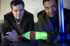 Media Lab postdoc Andreas Velten, left, and Associate Professor Ramesh Raskar with the experimental setup they used to produce slow-motion video of light scattering through a plastic bottle.