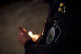 An MIT Police officer&#8217;s badge is illuminated by candlelight.