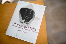 The cover of "Phantasmal Media" book is on corner of table.