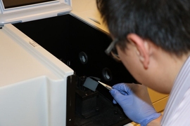 By patterning a solar absorber with tiny holes with diameters less than 400 nanometers, an MIT-Masdar Institute team has enhanced the range of solar energy that the device can absorb. Here, Masdar Institute postdoc Jin You Lu characterizes the nanoporous solar absorber using UV-Vis-NIR spectroscopy.
