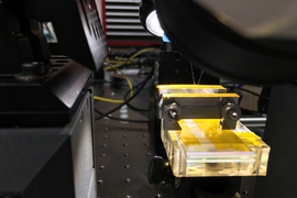 A view of the lab setup that was used to test the new materials, demonstrating that they could be stretched and flexed without losing the ability to confine light beams and carry out photonic processing.
