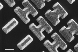 Scanning Electron Microscope image shows a few of the carefully designed shaped of the chalcogenide glass deposited on a clear substrate. The shapes, which the researchers call “meta-atoms,” determine how mid-infrared light is bent when passing through the material.