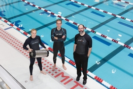 From left, graduate student Anton Cottrill, Professor Jacopo Buongiorno and Professor Michael Strano try out their neoprene wetsuits at a pool at MIT’s athletic center. Cottrill is holding the pressure tank used to treat the wetsuits with xenon or krypton.