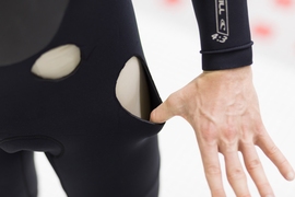 Holes in a wetsuit reveal the thickness of the neoprene material. The new MIT-developed treatment could provide the same amount of insulation with just half the thickness, the researchers say.