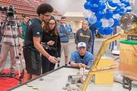 A 2.007 instructor measures the speed at which a student’s robot spins a wheel — one of several point-scoring tasks.