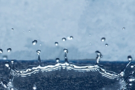 Droplets that land on a specially prepared surface with tiny ring-shaped patterns splash upward in a bowl shape, as seen in this photo, instead of spreading out over the surface, thus minimizing the water’s contact with the surface.