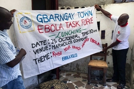 Residents hold a sign announcing a neighborhood meeting as part of Liberia’s effort to stop the spread of Ebola, in October 2014. A new study shows how a volunteer outreach campaign helped people understand and cooperate with government efforts to control the disease.