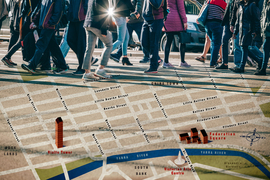 A digital collage focuses on the legs of people walking on pavement, with a map of Melbourne superimposed on the background.