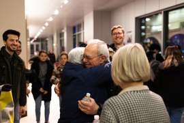 President Reif hugs someone while other members of the community smile around him