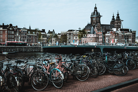 Rows of bikes are parked near a canal in beautiful Amsterdam.