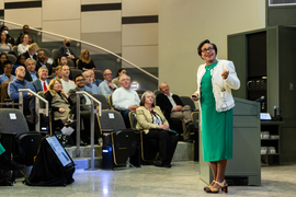 Paula Hammond presents in front of seated audience in lecture hall while facing towards stage