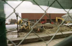An earth-shaking pile driver on the site of the new athletic center is viewed through a small hole in the fence covering near the Dupont walkway.