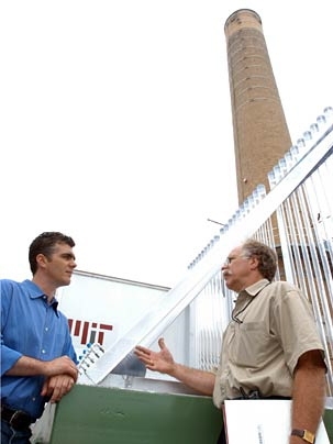 Inventor Isaac Berzin, left, converses with Peter Cooper, director  of  utilities in MIT's Department of Facilities, atop MIT's cogeneration plant. Berzin's company, GreenFuel, is installing bioreactors consisting in part of  temperature-controlled tubes, at right, which will hold algae through which waste gases will pass.