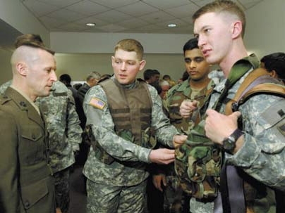 Owen Fogarty (center), a member of a West Point team competing in the Soldier Design Competition, demonstrates his team's hands-free, casualty-carriage system for Lt. Col. Shawn Reinwald of the U.S. Marine Corps, who judged the competition. Team members Jamie Pittman (wearing the device) and Venkat Motupalli look on.