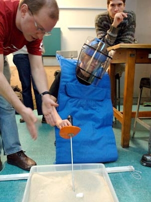 Andrew Heafitz, an instructor at the Edgerton Center, shows graduate student Olivia Leitermann, in protective gear, how to locate a mine during the IAP session 'MIT Design for Demining,' held Wednesday, Jan. 18.