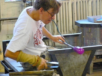 Peter Houk, technical instructor and glass artist in the MIT Glass Lab, blows glass through a tubing pipe.