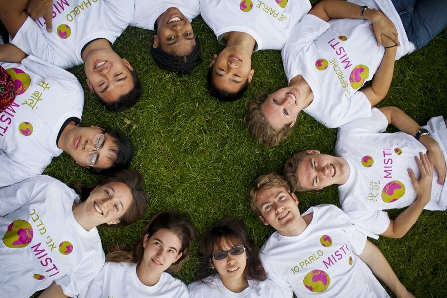 Students lying on their backs in a circle, with heads in the center, photographed from above