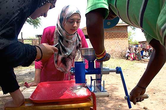 Arfa Aijazi (center) demonstrated how to grind corn into flour with a hand-powered burr mill with Fareeha Safir '13 at a village outside of Arusha, Tanzania, in 2011.