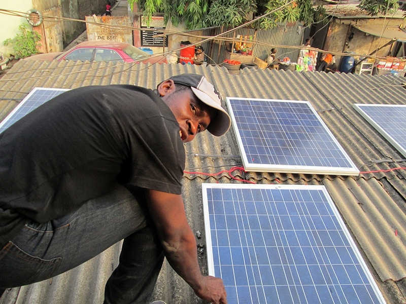 Chidube Ezeozue checks solar panel mountings and connections on a rooftop.