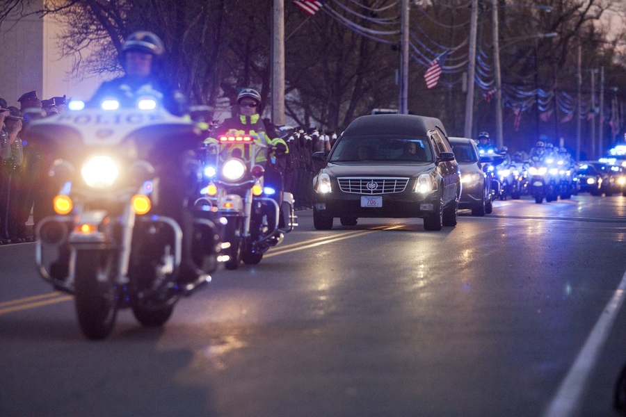 A hearse transporting MIT Police Officer Sean Collier passes down Church Street near the Town Common in Wilmington, Mass.