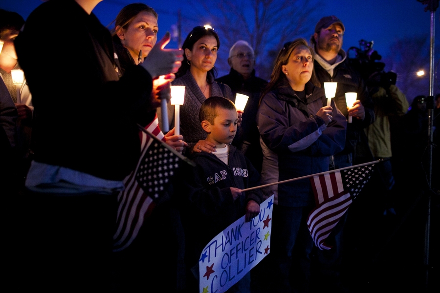 Lisa Marriott and her son, Joseph, hold a sign and candles during the vigil for Collier.