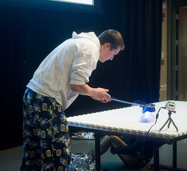A student from Team Hedgehog sets up the Light Tracers toy, in which remote-controlled toy cars leave a trail of light on the tabletop.