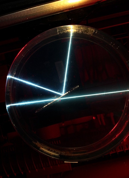 Seen from above, two white beams reaching the sample material  either pass through or are reflected, because of a slight difference in the angle of approach.