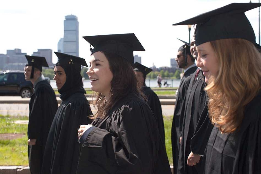 Graduates process along the Charles River, with the Boston skyline in the background, en route to Killian Court.