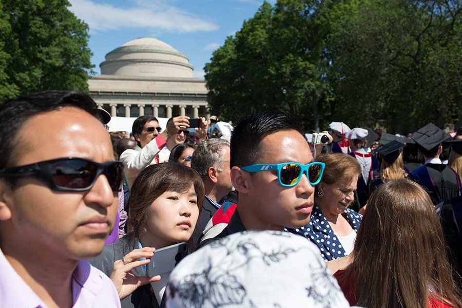Family and friends gather to watch — and take photos — as the new graduates enter Killian Court.
