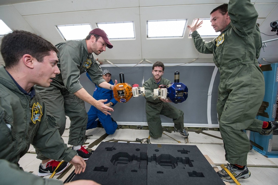 Aboard NASA’s reduced-gravity aircraft (from left), grad student David Sternberg, Aurora engineer Roedolph Opperman, an unidentified NASA engineer, grad student Duncan Miller, and NASA crew member Eric Katterhagen prepare two SPHERES microsatellites for a docking maneuver.