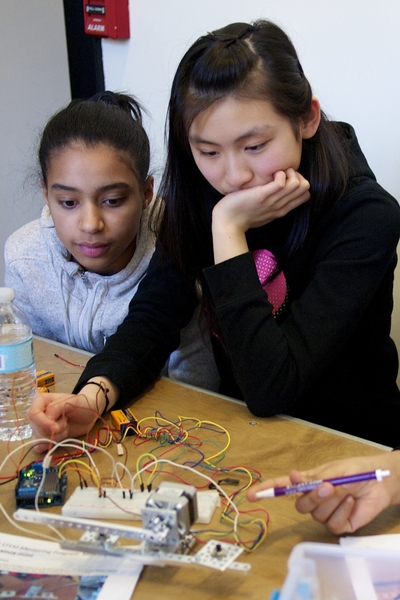 Students Leah Delacruz and Emily Sun build a circuit to connect their arm muscles to nodes and powering a robot arm.