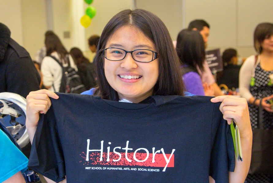 A student at a previous TOUR de SHASS poses with a free t-shirt.