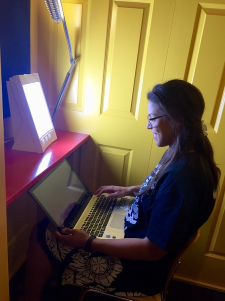 A fourth-year PhD student in electrical engineering and computer science, Ariel Anders works beside a light-therapy box recently installed in the Stata Center.