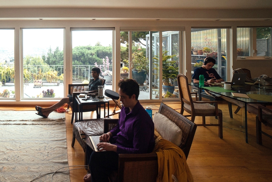 Laser Nite (front, right) and Anish Athalye in the living room of the Sandcastle. Sophomore Logan Engstrom works at the kitchen table after crashing at the house the night before.