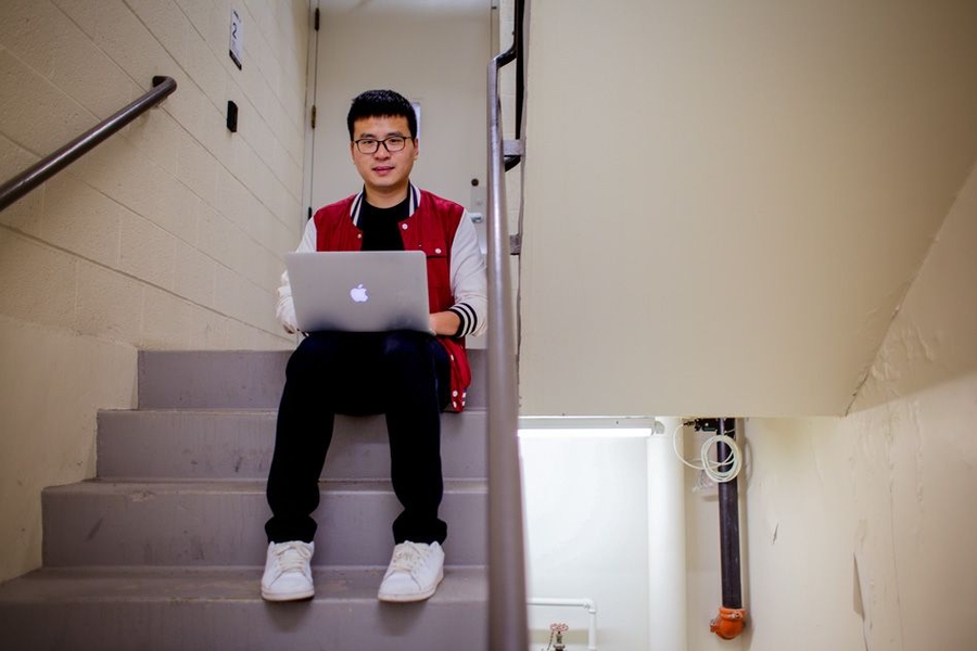 CEE postdoc Hao Sun sits in a stairwell in the Green Building. On the right attached to the ceiling is one of the accelerometers used to monitor the building.