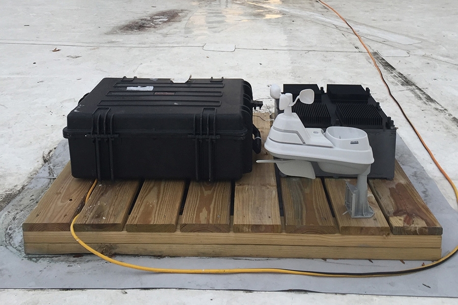 The team’s test device, which has been deployed on the roof of an MIT building for several months, was used to prove the principle behind their new energy-harvesting concept. The test device is the black box at right, behind a weather-monitoring system (white) and a set of test equipment to monitor the device’s performance (larger black case at left).