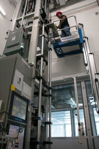 AFFOA Senior Technician Chhea Chhav sets up a run through a fiber drawing tower, in this case for fiber containing green LEDs. A 17-inch cylinder, called a preform, will be drawn out to yield up to 420 meters of fiber with diameters from 4 to 200 microns.