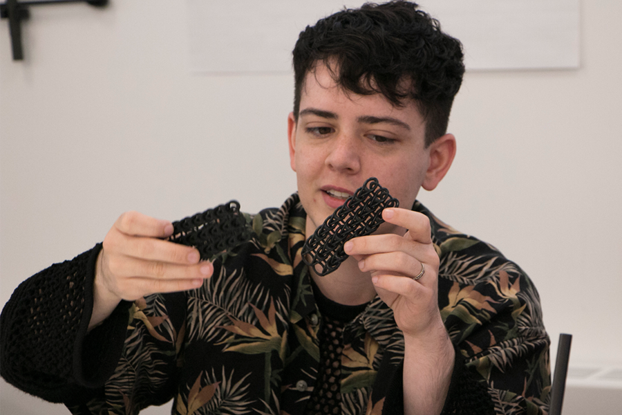 Fashion Institute of Technology rising senior Jesse Doherty holds a 3-D-printed rubber mesh with a large, open pattern during the first week of a Workshop in Advanced Functional Fibers and Fabrics at MIT.