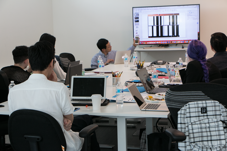 AFFOA Chief Operating Officer Tairan Wang (kneeling center) demonstrates how to use a smartphone to read a bar code embedded in a backpack and pair it with a web-based social network. A sample backpack, woven with a unique identifier, sits on the chair in the foreground. AFFOA’s goal is to take the novel functionality from research to commercial application.