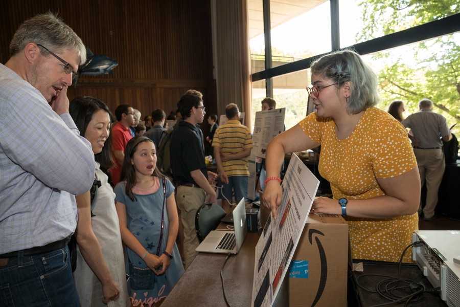 Isabel MacGinnitie, a student in the Build a Cubesat course, explains the cubesat project to visitors at the Stratton Student Center.