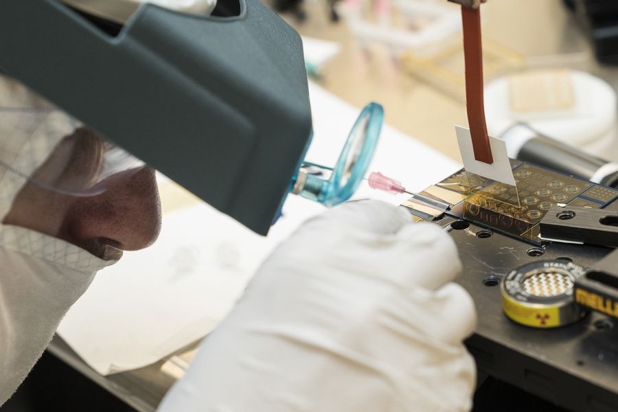 Jakub Kedzierski aligns the polyimide layer, yellow and translucent, on top of the electrode layer. Each small circle and square seen etched in the polyimide is a single actuator, either a rotational or linear actuator respectively.