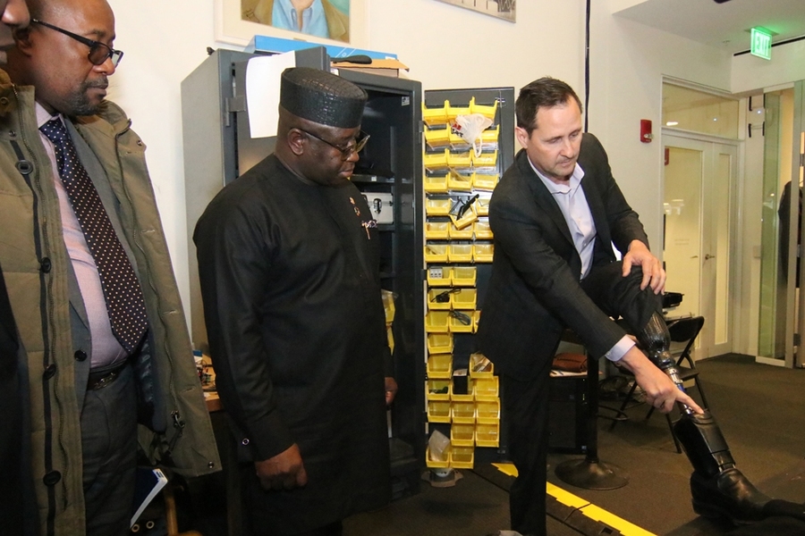 Hugh Herr, director of the Media Lab’s Biomechatronics group, right, shows Sierra Leone President Julius Maada Bio, center, some of the features of his own high-tech prosthetic leg, developed at the lab.