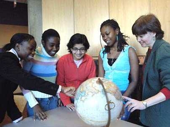Students participating in the MIT Hosts to International Students program identify their home countries on a globe as MIT staff member Janet Fischer, right, looks on. Since 2002, Fischer has been a host to, from left, Zawadi Lemayian, a freshman from Kenya; Irene Berita Murimi, a junior from Kenya; Smeet Deshmukh, a graduate student from India; and Tendai Chizana, a senior from Zimbabwe.