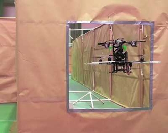 A small, autonomous helicopter, programmed by MIT students under the direction of Professor Nick Roy, passes through a simulated window as part of a competition held over the summer.